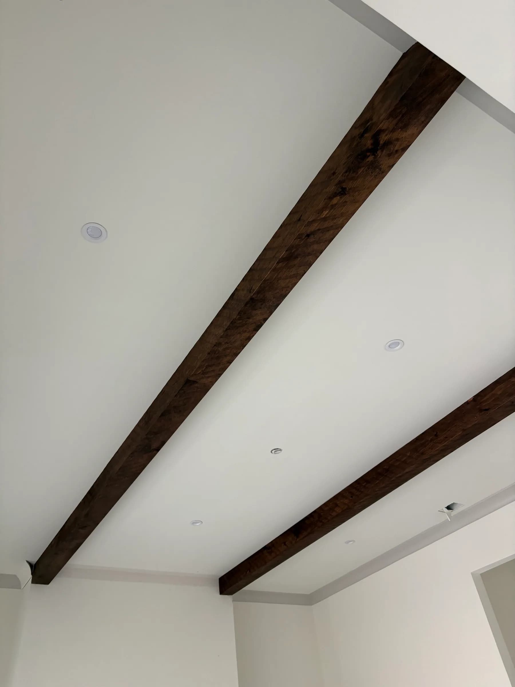 Two dark-stained beams running the length of a white ceiling.
