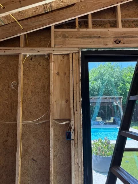 Framing around a new steel-framed window, looking out to a pool and pergola.
