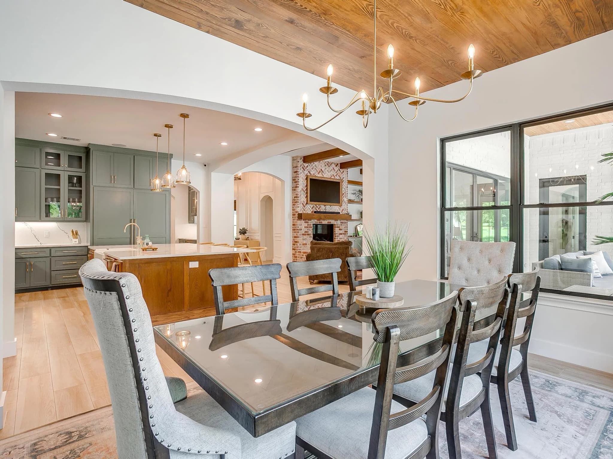 From the breakfast table through an arch to the kitchen island and the brick fireplace beyond.
