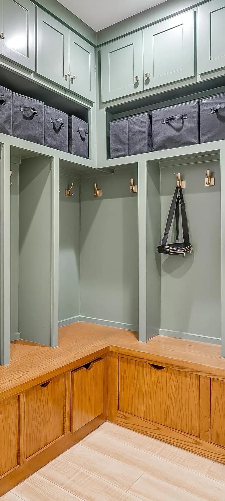 The mudroom: sage lockers with hooks and a wood bench, closed cubbies above.