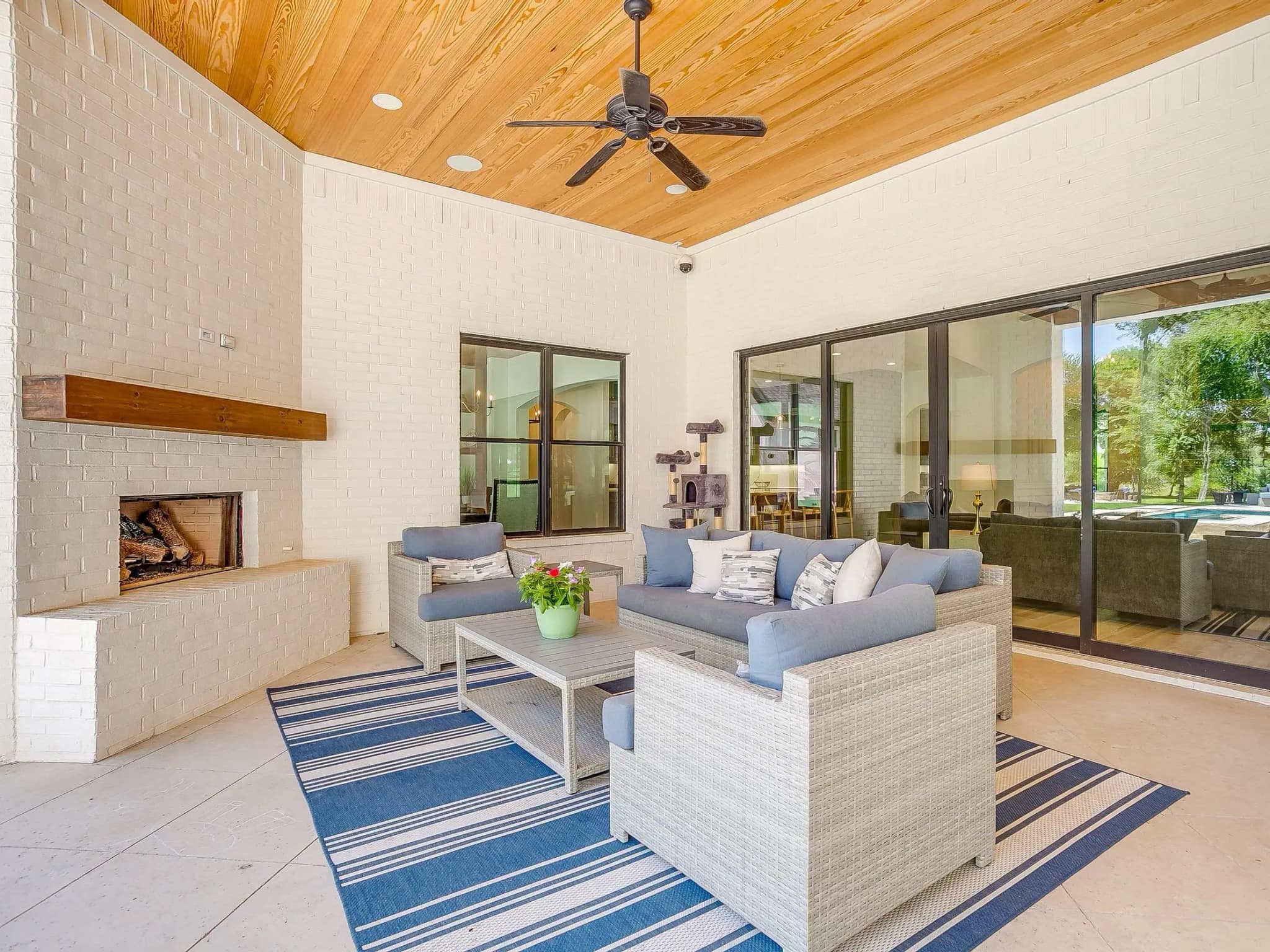 Seating under the patio's wood ceiling, with sliding glass doors into the living room and the brick fireplace to one side.