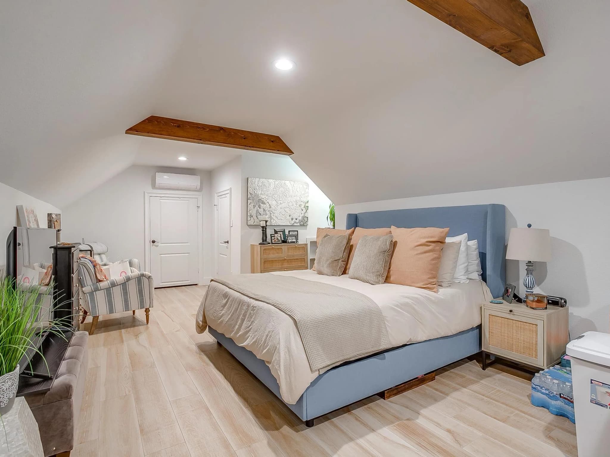 A bedroom under the garage roof, a bed against the sloped wall and a door through to the bath.