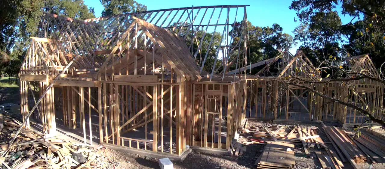 The timber frame standing on the slab, roof framing set over one gable.