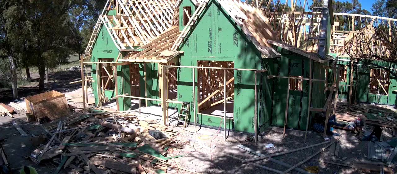 Green sheathing going on over the frame, the roof still open above it.